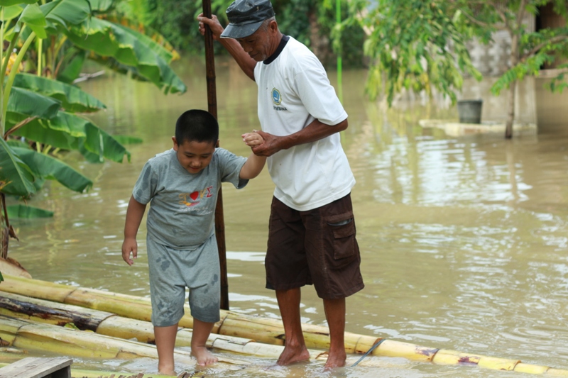 Seorang Kakek dan cucunya menyeberangi genangan air menuju tempat pengungsian .. Creadit : ALI FOTO